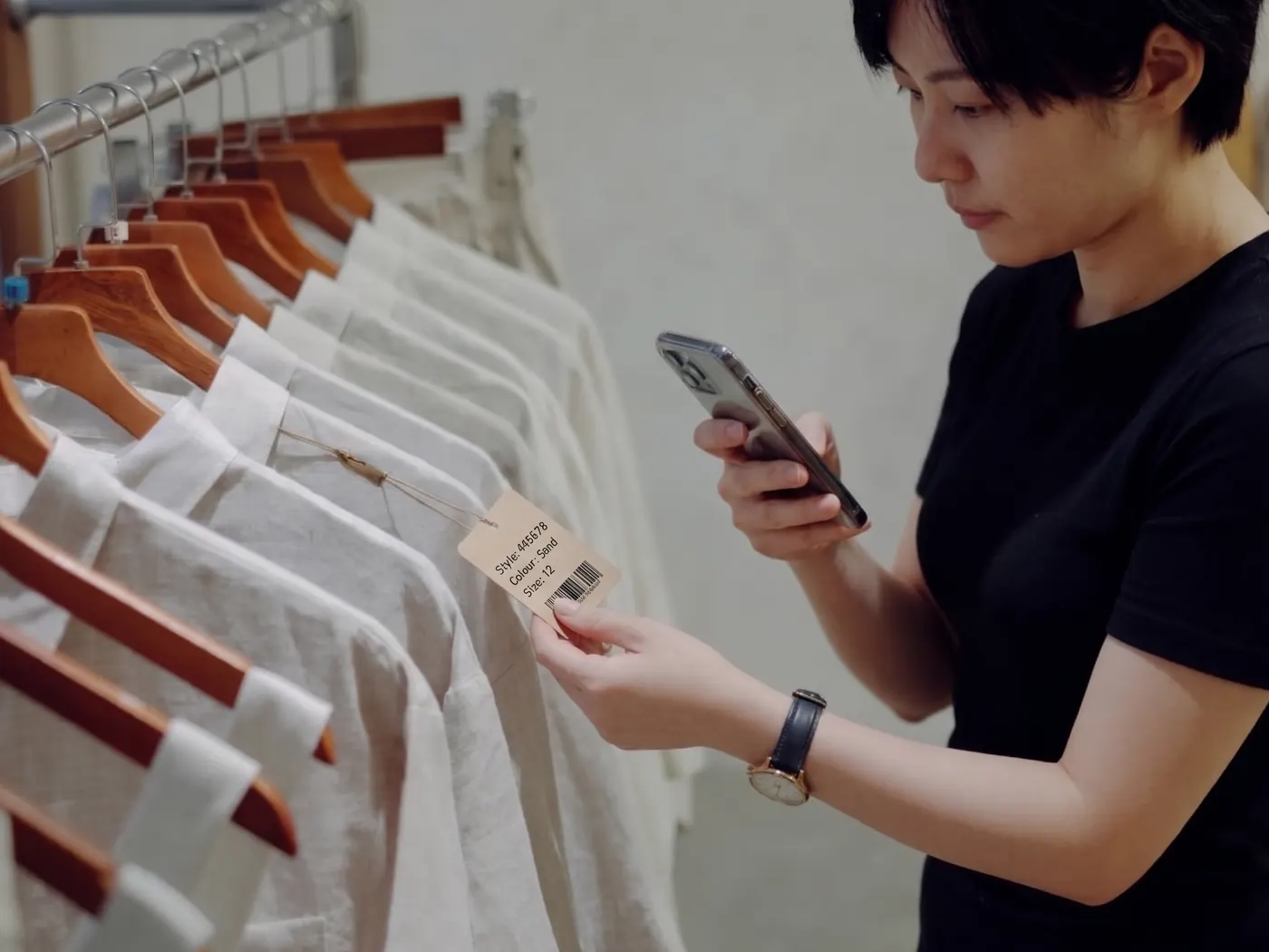 A shop owner snapping a shirt's swing tag with a phone